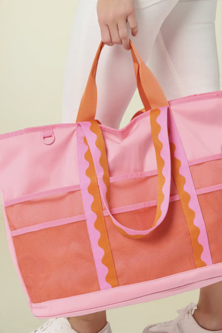 Person holding a pink and orange tote bag against a white background