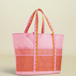Pink and orange tote bag with striped handles on a white background