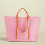Pink tote bag with orange handles and decorative elements on a white background