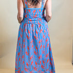 Person wearing a blue and red patterned dress against a plain background