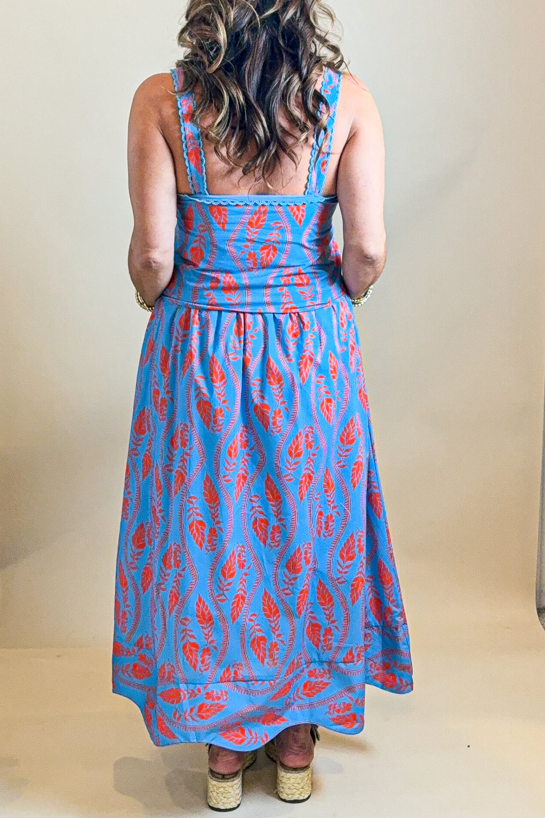 Person wearing a blue and red patterned dress against a plain background