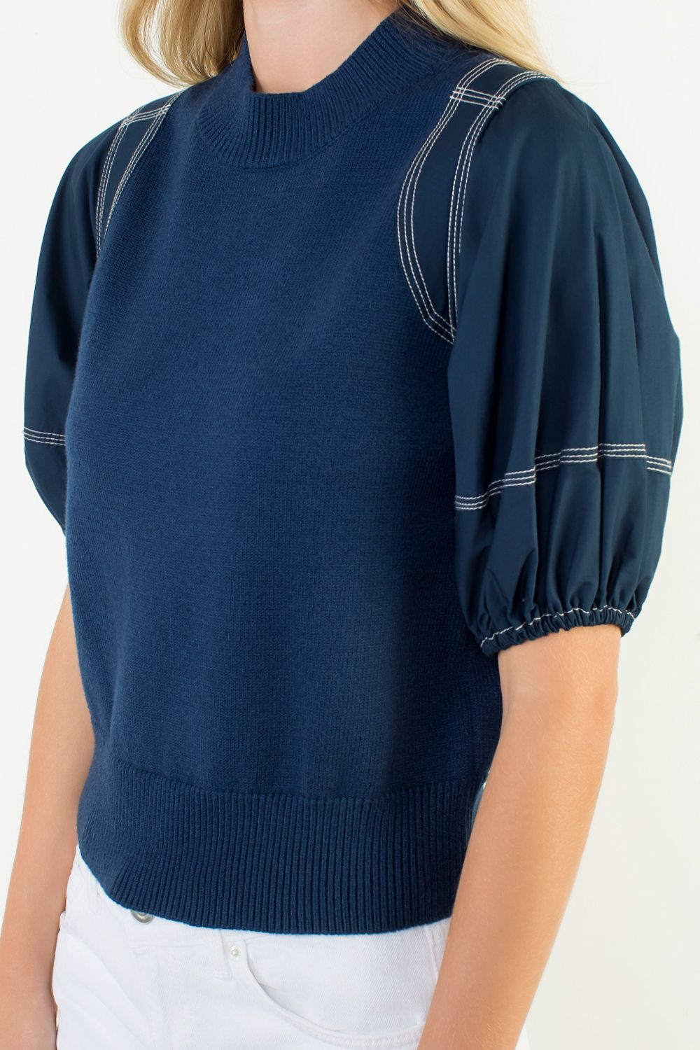 Navy blue sweater with puff sleeves worn by a person on a white background