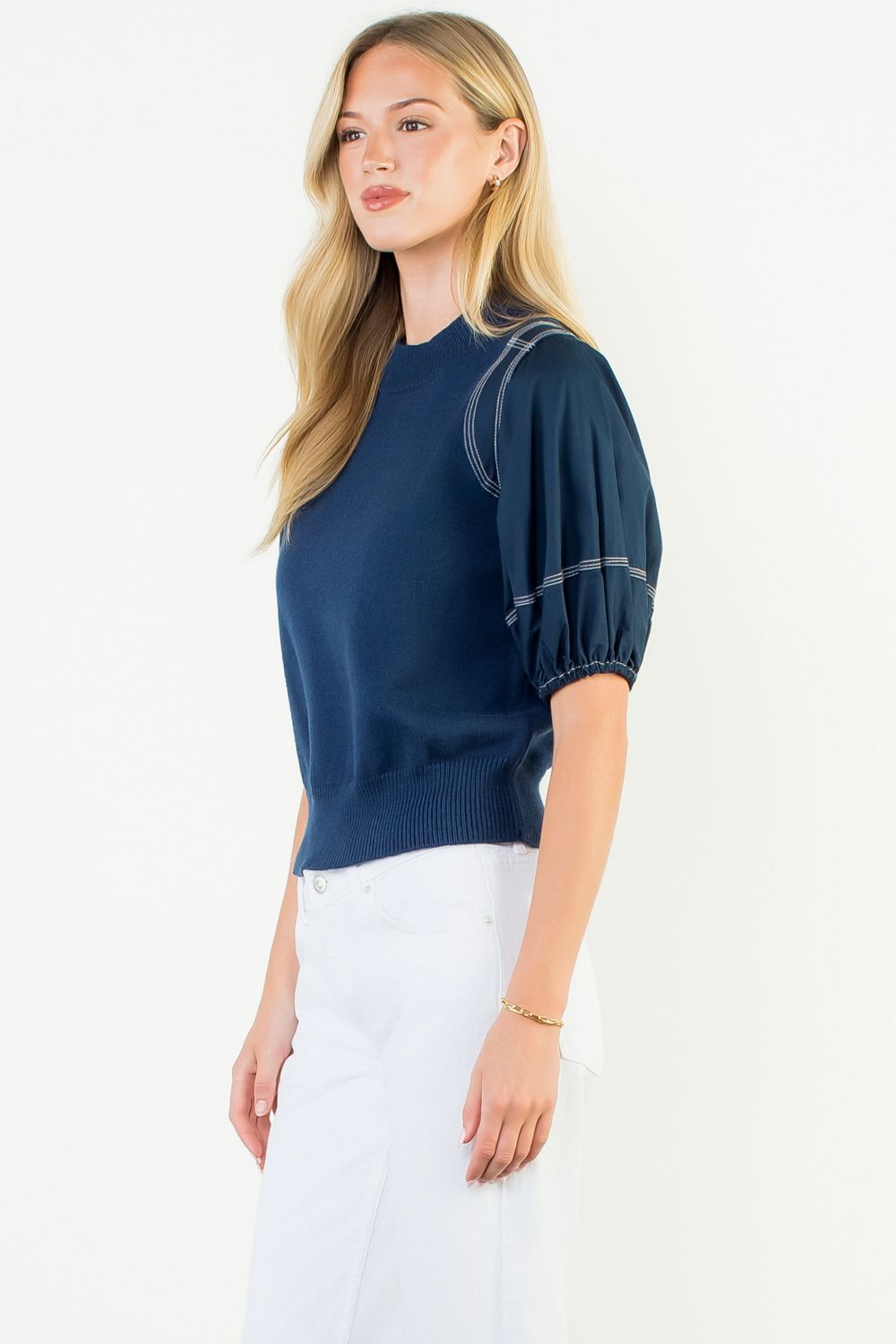 Woman wearing a navy blue blouse with puff sleeves on a white background