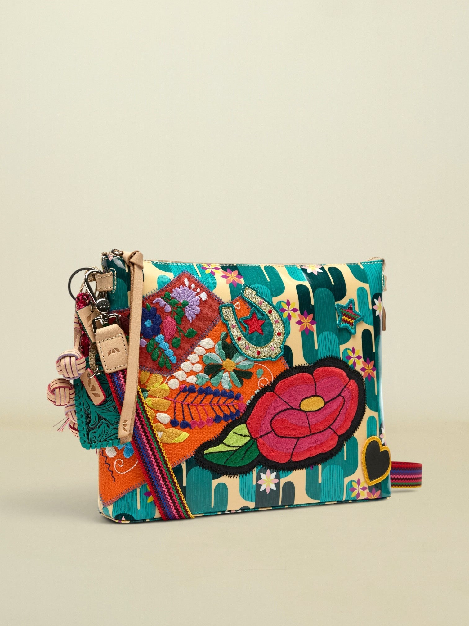 Point of Origin CONSUELA Desi Downtown crossbody bag with cactus print, colorful floral embroidery, horseshoe patch, and tassel.