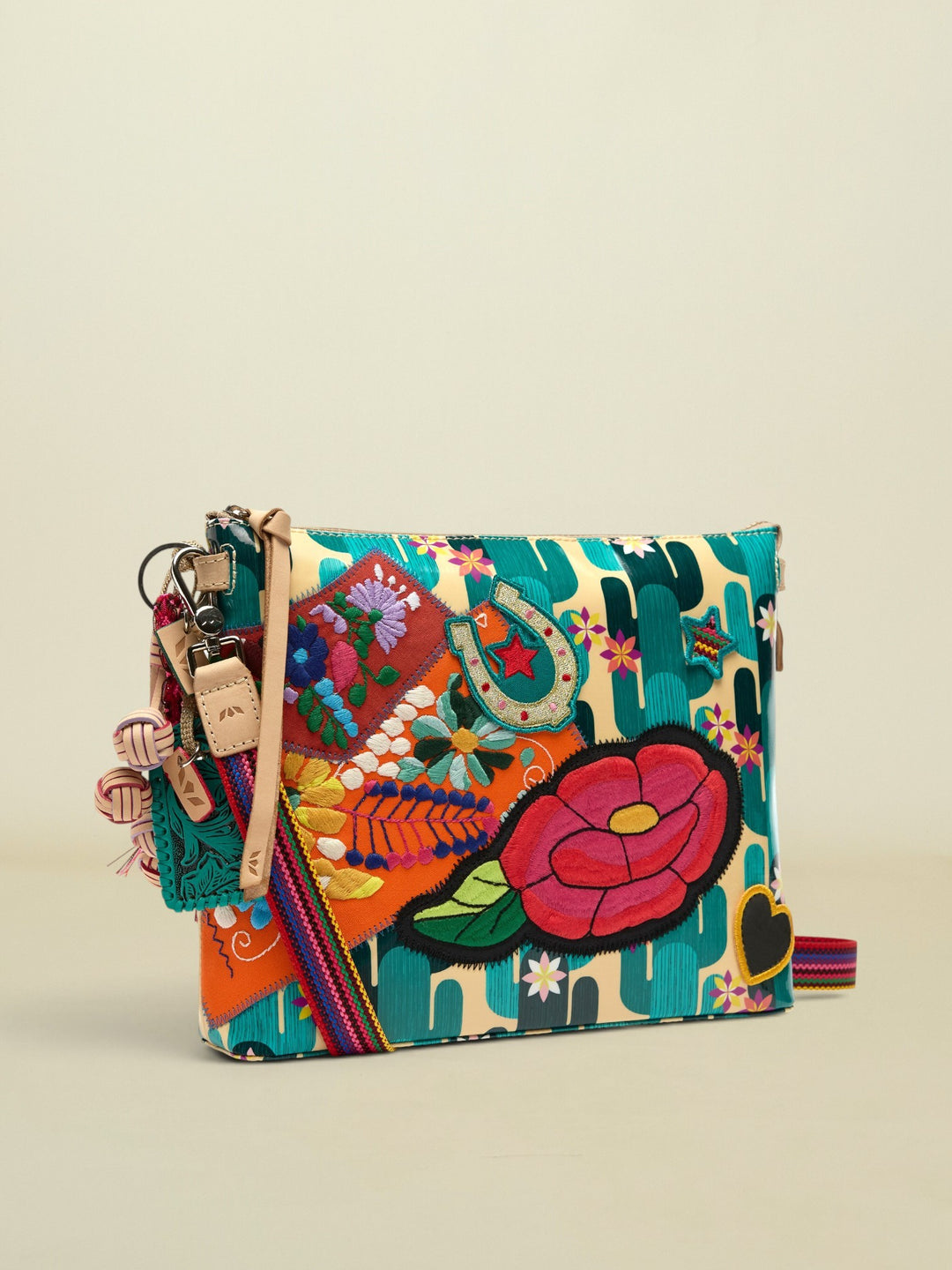 Point of Origin CONSUELA Desi Downtown crossbody bag with cactus print, colorful floral embroidery, horseshoe patch, and tassel.