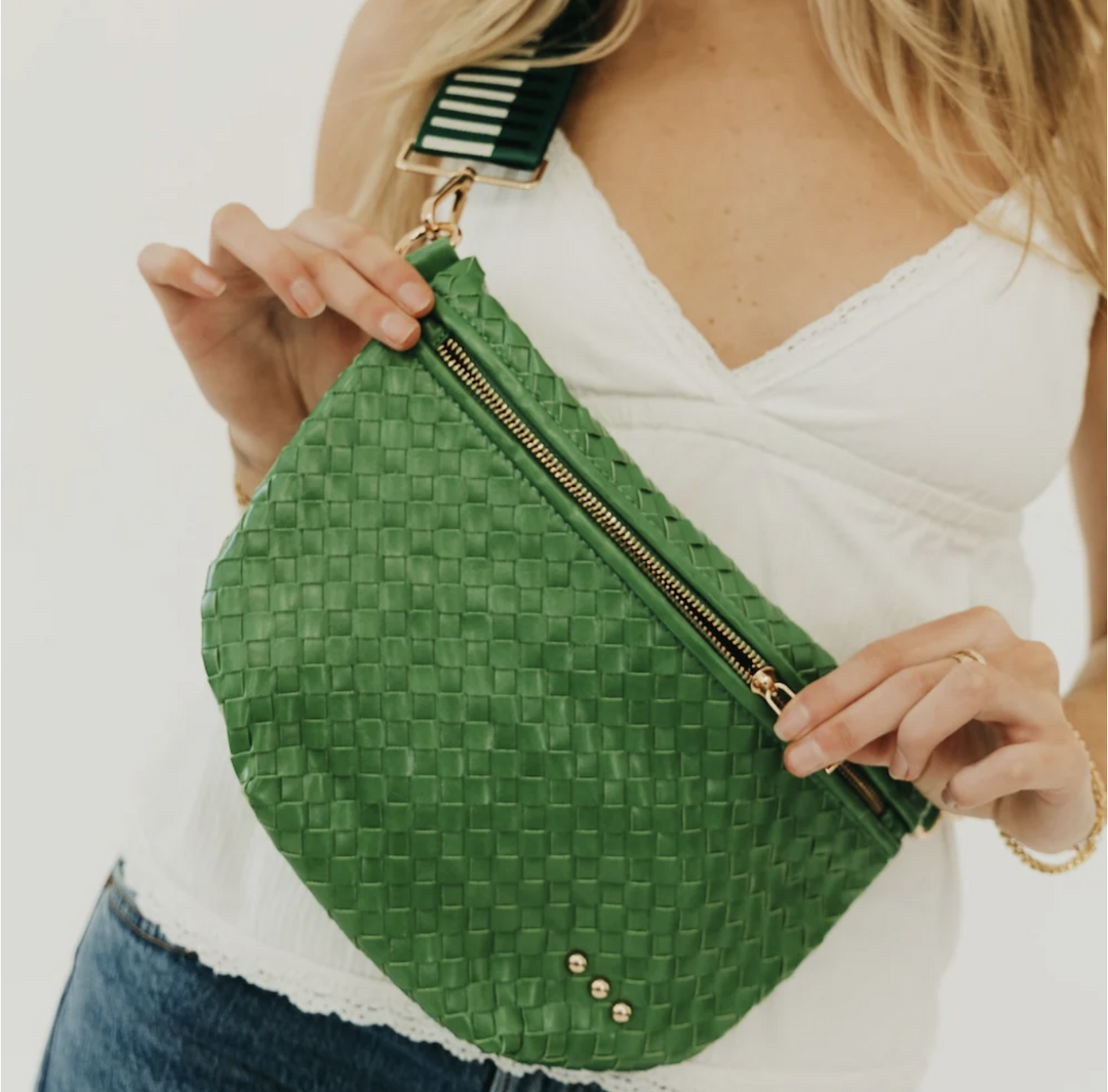 Green woven fanny pack held by a person wearing a white top.