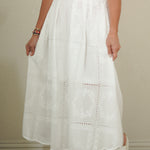 Person wearing a white skirt and red top against a neutral background