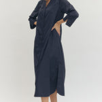 Woman wearing a navy blue dress with cut-out sides on a white background