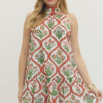 Woman wearing a sleeveless dress with a floral pattern on a plain background