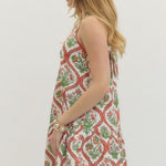 Woman wearing a sleeveless dress with a floral pattern on a plain background