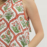 Woman wearing a sleeveless top with a floral pattern on a plain background