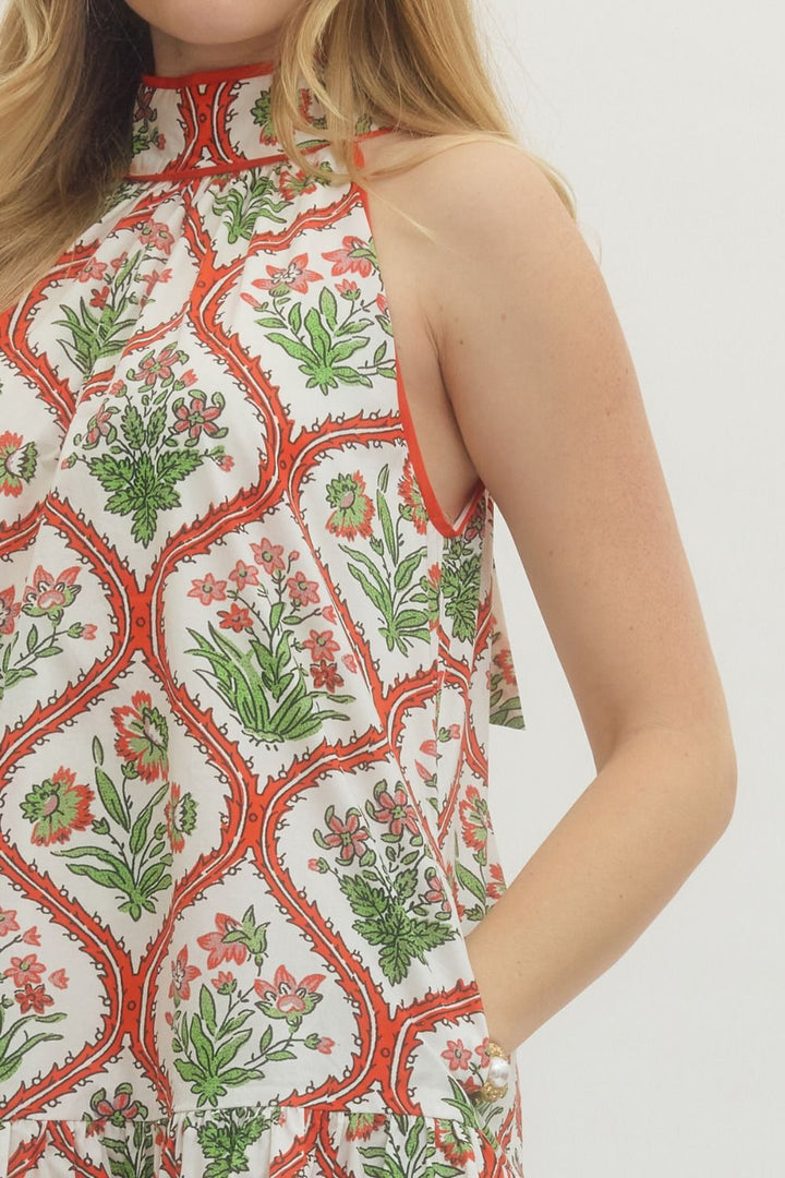 Woman wearing a sleeveless top with a floral pattern on a plain background