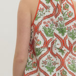 Woman wearing a halter neck top with a floral pattern on a plain background