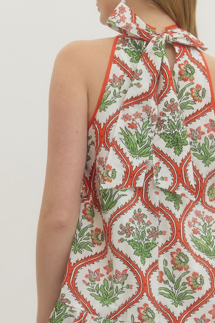Woman wearing a halter neck top with a floral pattern on a plain background
