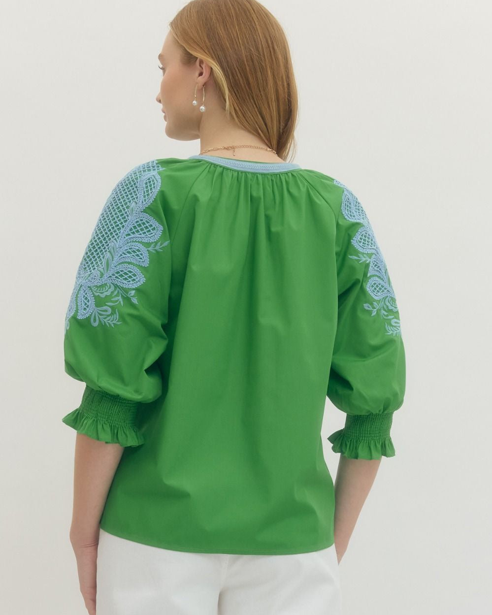 Green blouse with blue embroidery on a white background