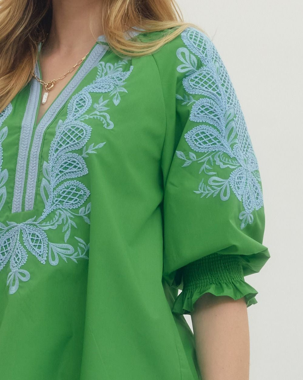 Green blouse with white embroidery on a plain background