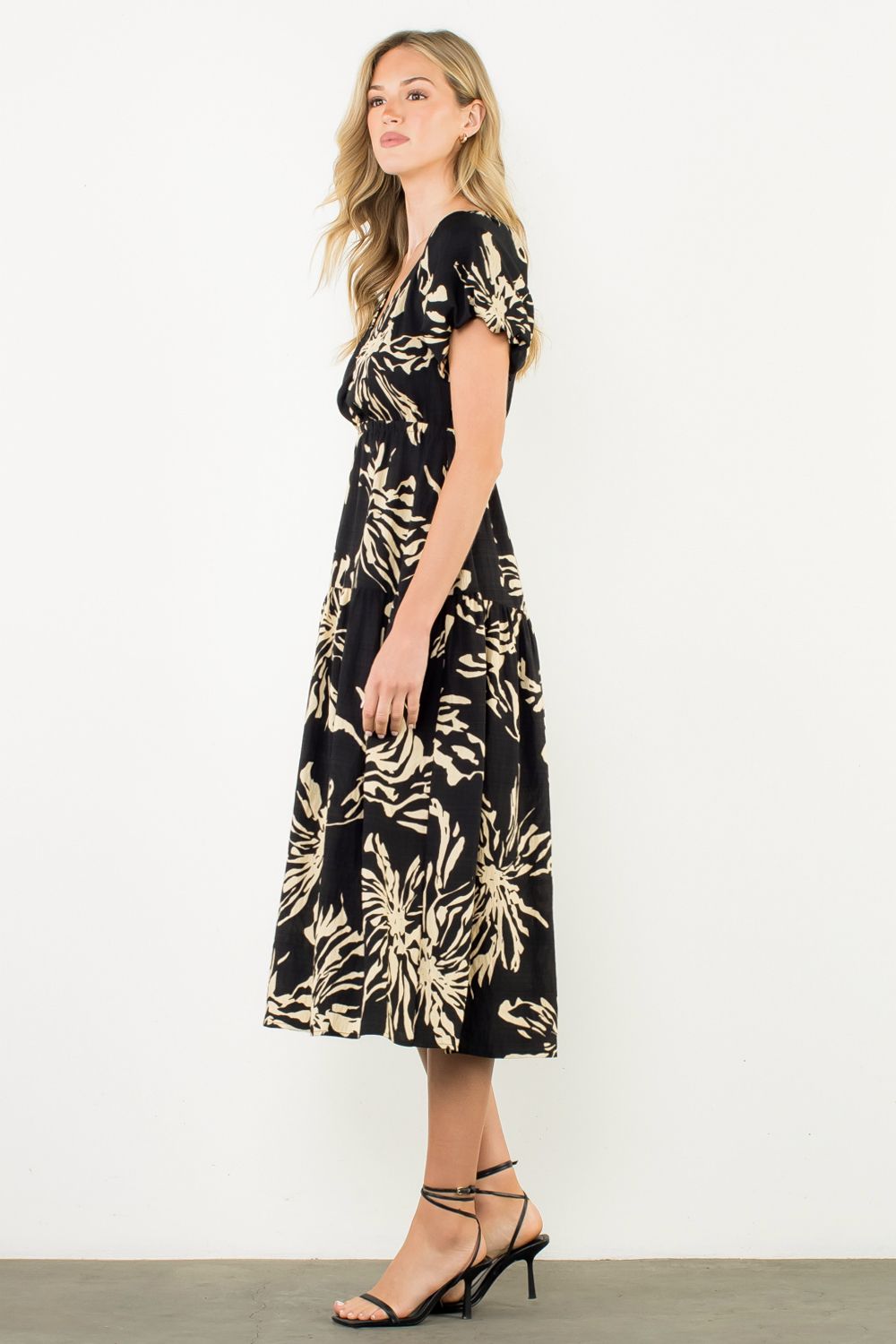 Woman wearing a black dress with gold floral pattern on a white background