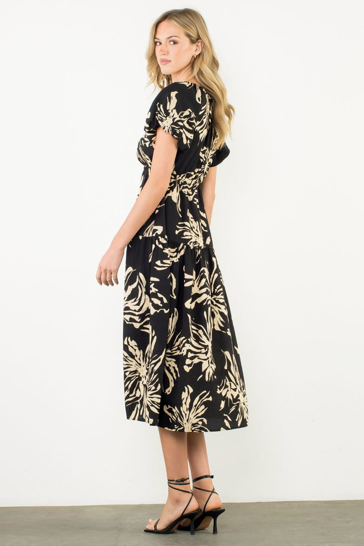 Woman wearing a black dress with gold leaf pattern on a white background