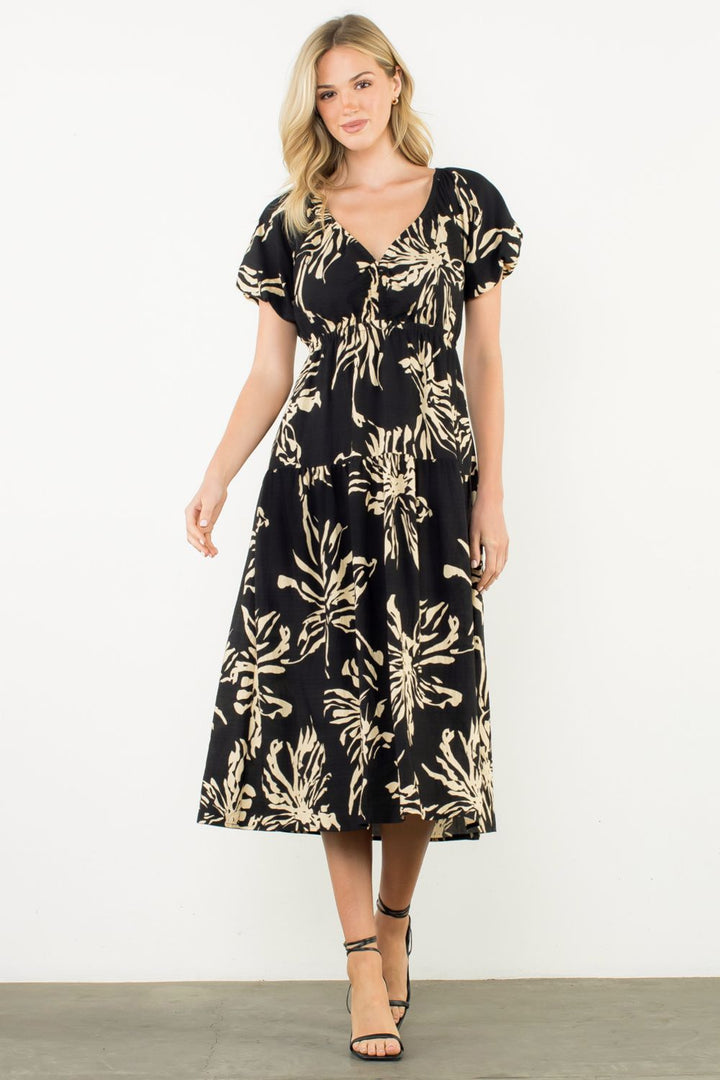 Woman wearing a black dress with gold floral pattern on a white background