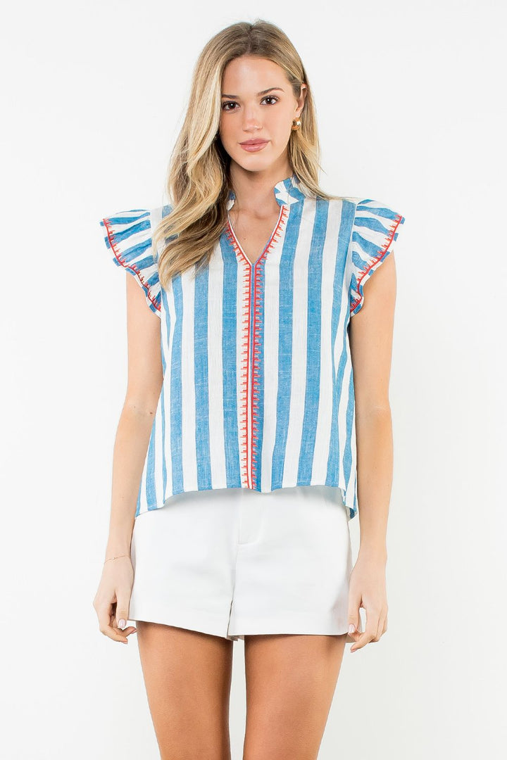 Woman wearing a blue and white striped sleeveless top with red accents on a white background