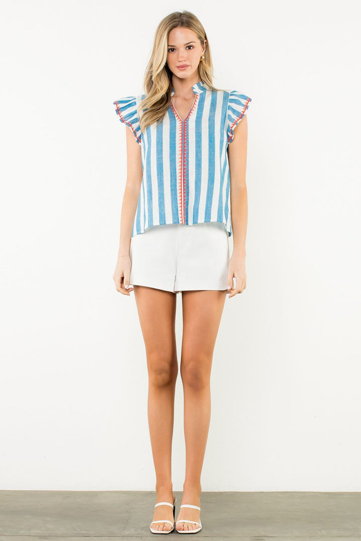 Woman wearing a striped shirt and white shorts on a plain background