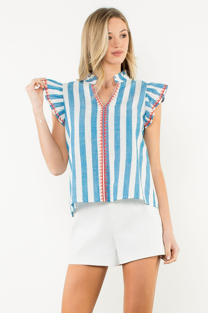 Woman wearing a blue and white striped top with red accents on a white background