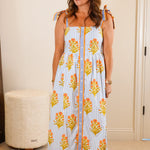 Woman wearing a floral dress standing in a bedroom.