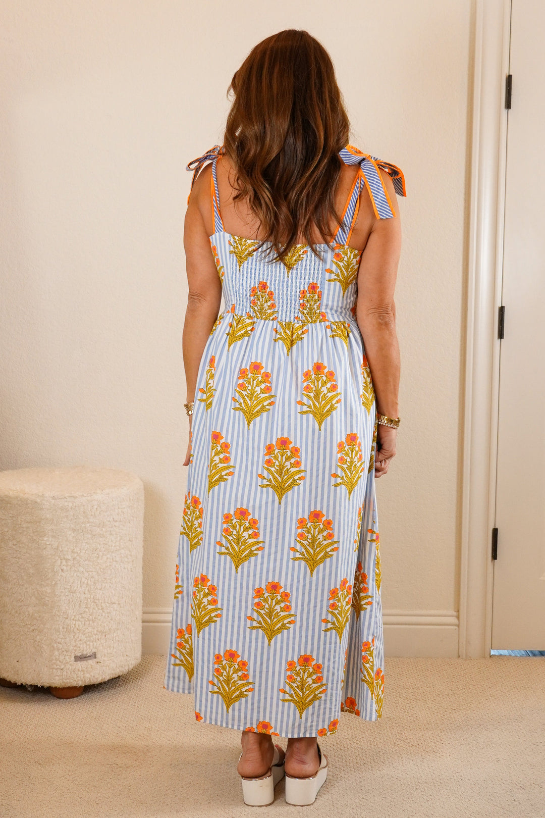 Woman in a floral dress standing in a bedroom