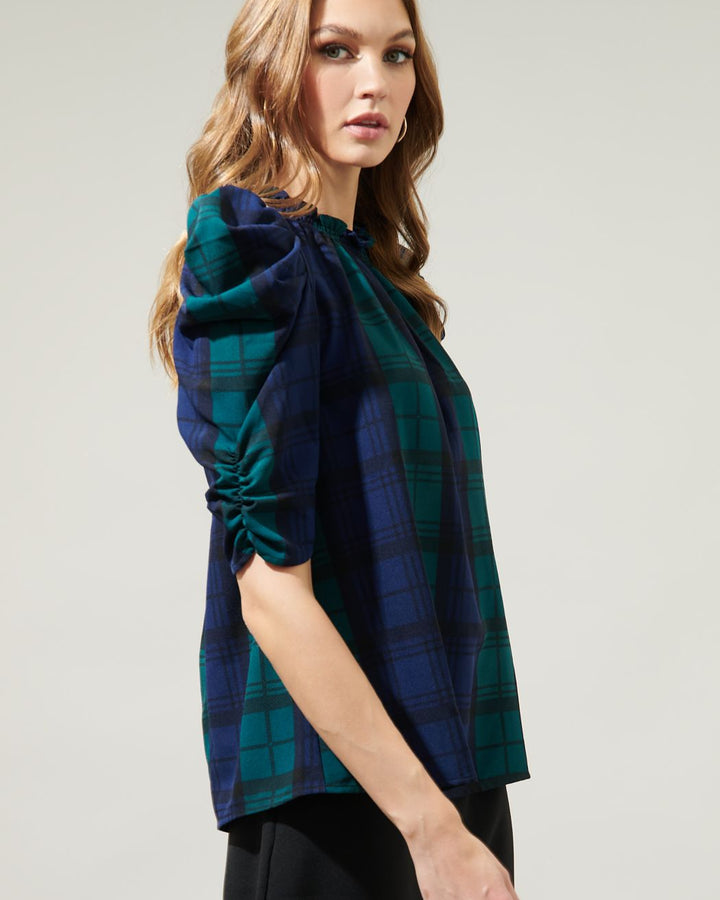 Woman wearing a blue and green plaid shirt on a plain background