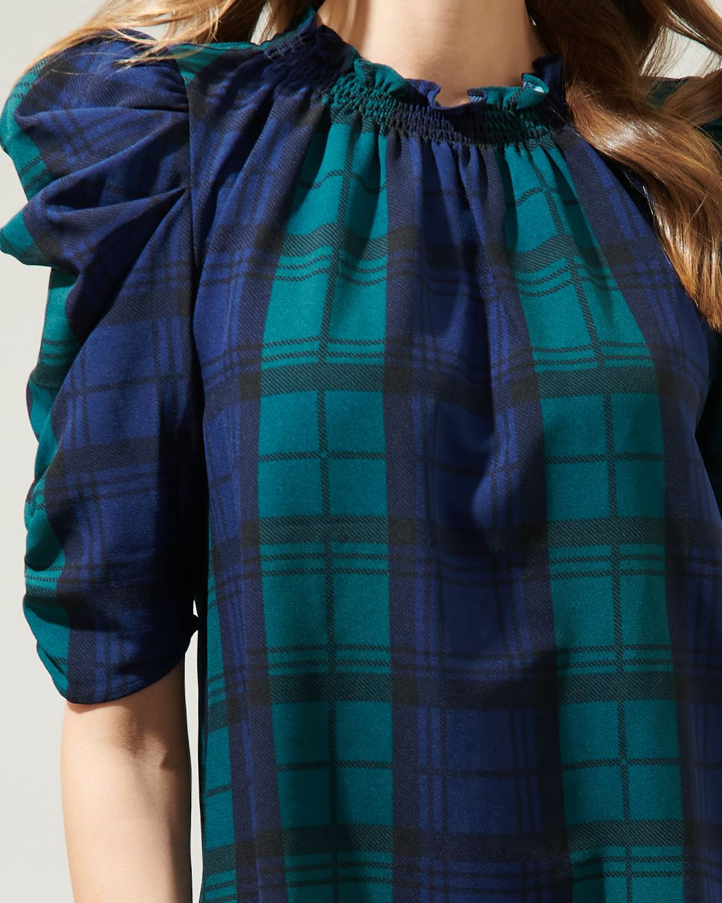 Blue and green plaid dress with a close-up of the neckline on a plain background