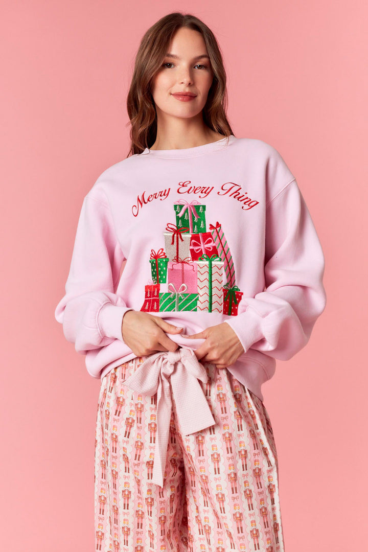 Woman wearing a pink sweatshirt with gift design and text on a pink background