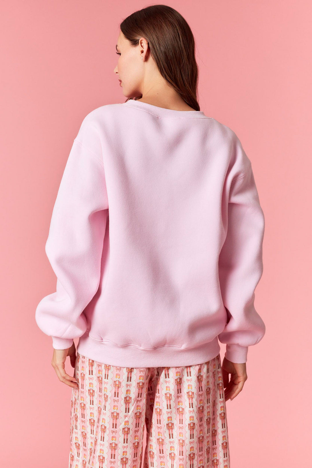 Person wearing a pink sweatshirt against a pink background