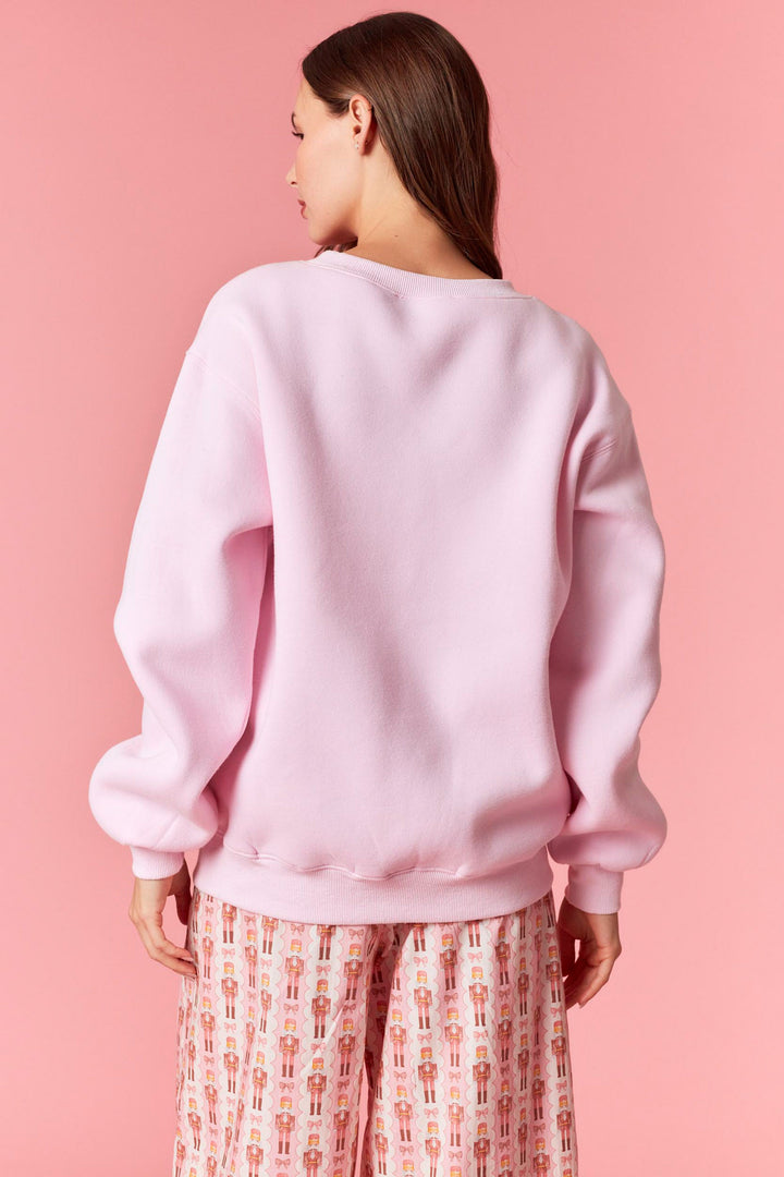 Person wearing a pink sweatshirt against a pink background