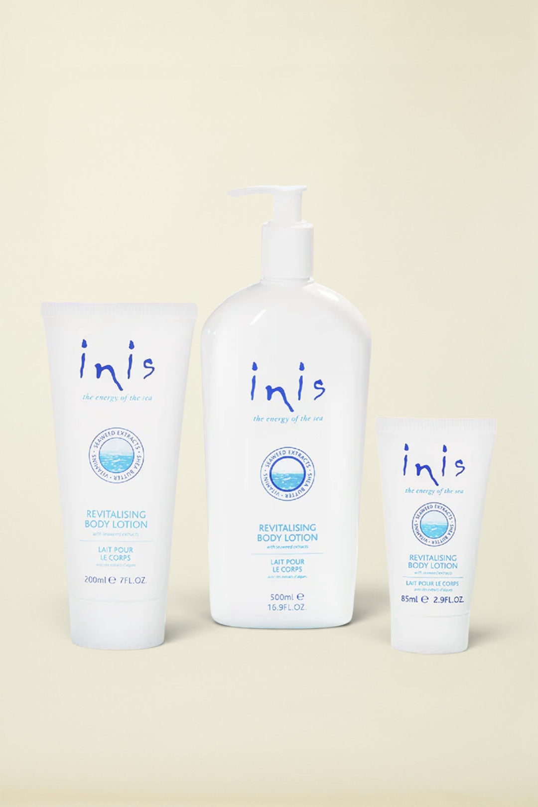 Three white Inis Revitalising Body Lotion containers on a light blue background: a 200ml squeeze tube, a 120ml pump bottle, and a 8ml travel tube, with a small silver foil pack at the lower left.