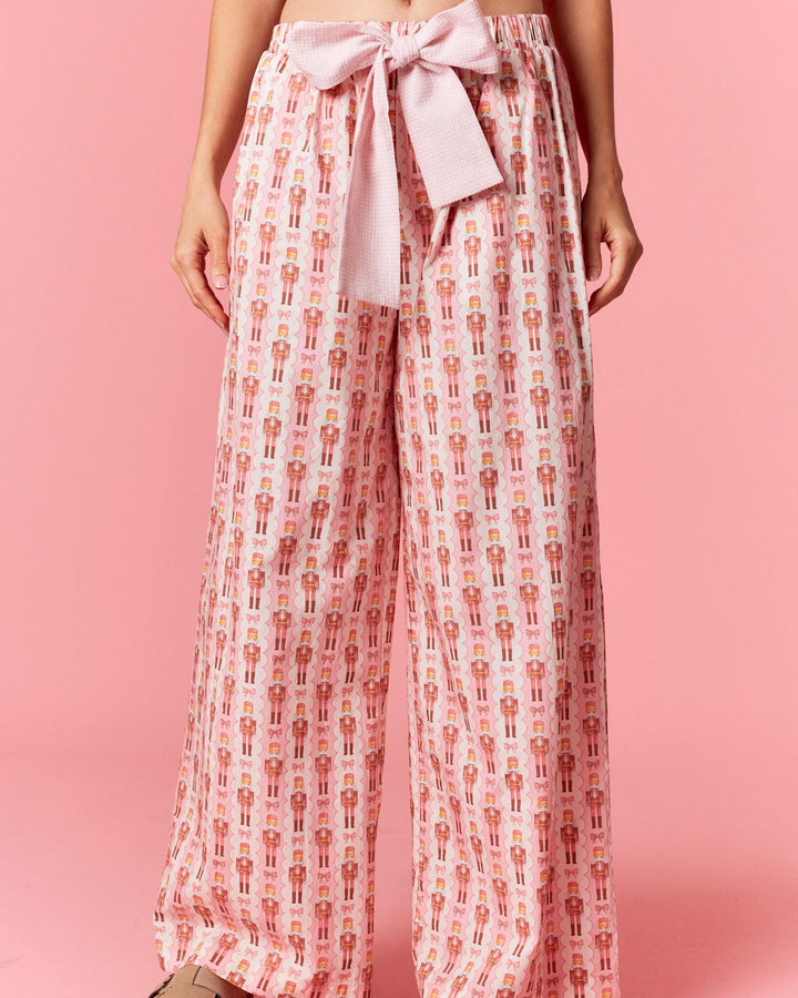 Person wearing patterned pants with a pink bow on a pink background