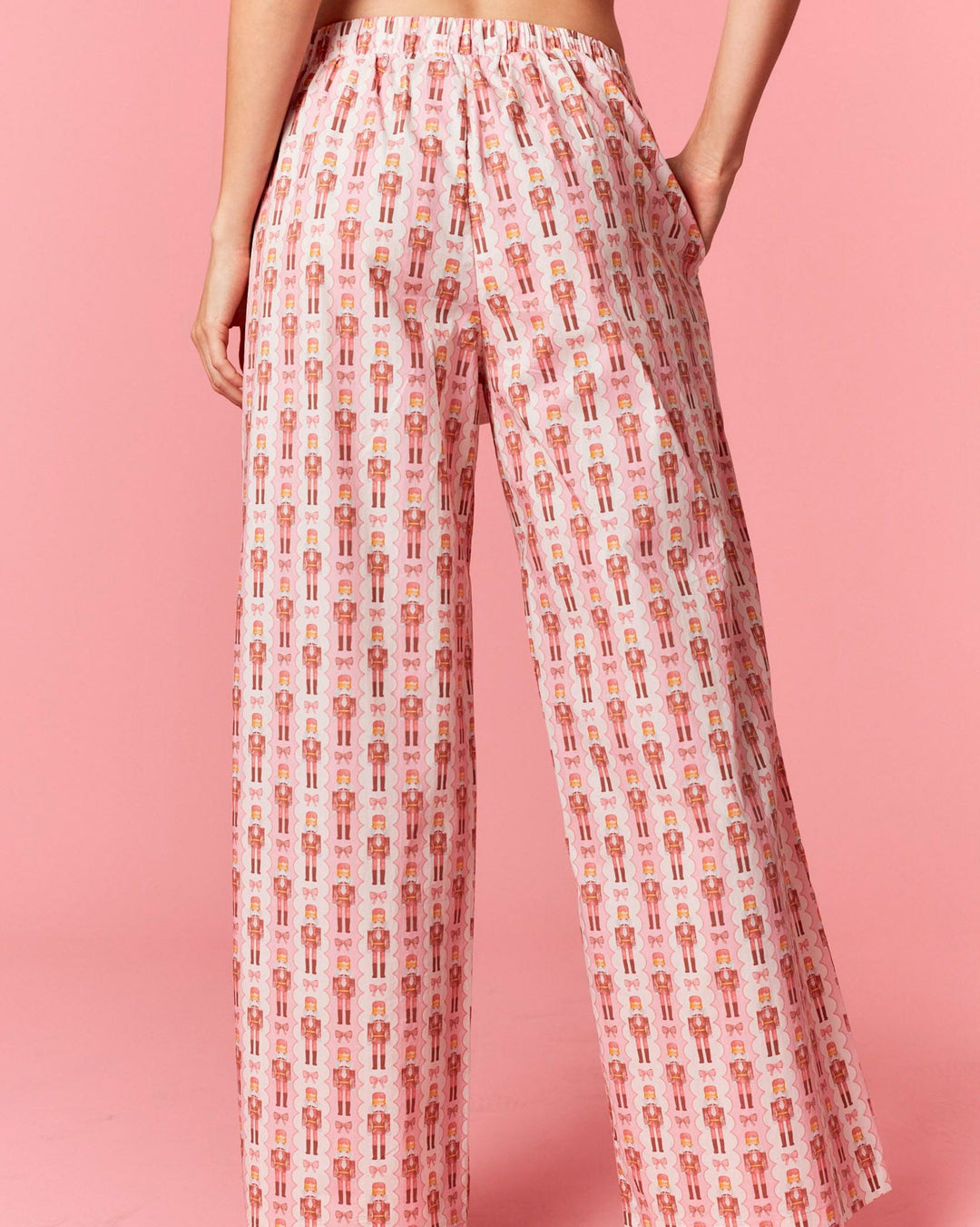 Person wearing a patterned wide-leg pants on a pink background
