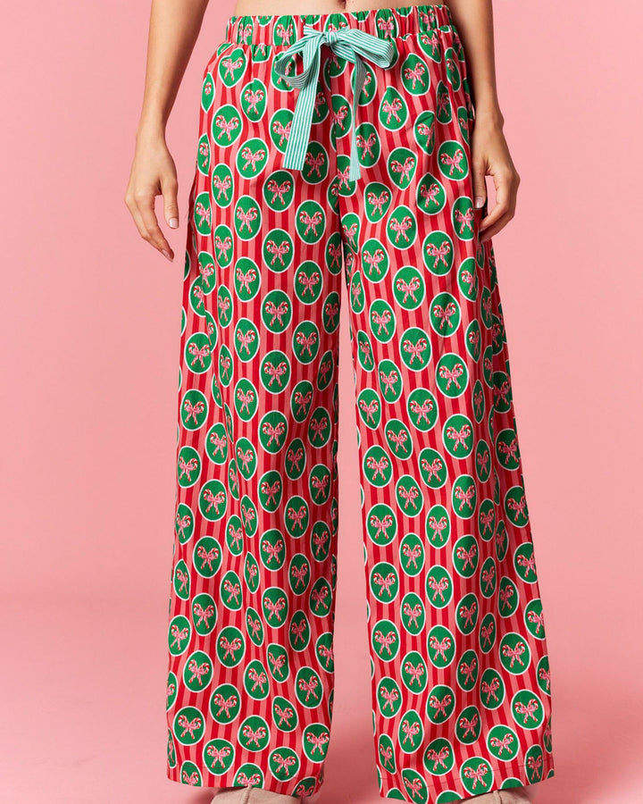 Person wearing red and green patterned pants on a pink background