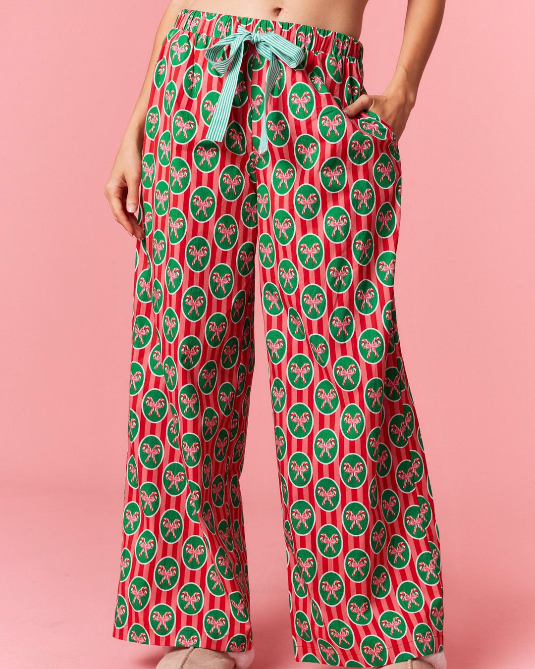 Person wearing red and green patterned pants on a pink background