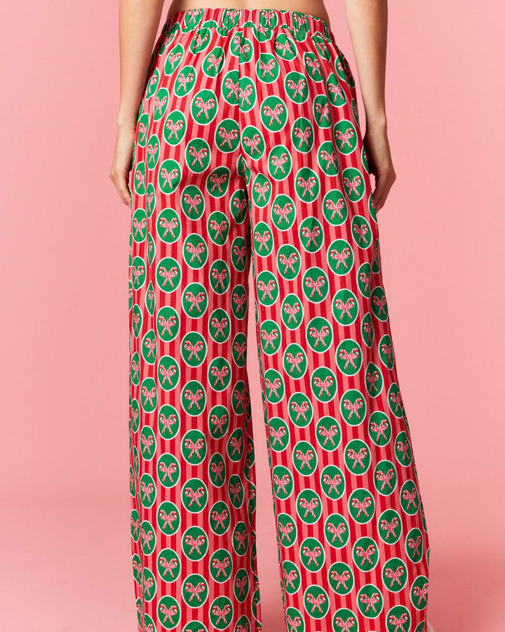 Person wearing red and green patterned pants on a pink background