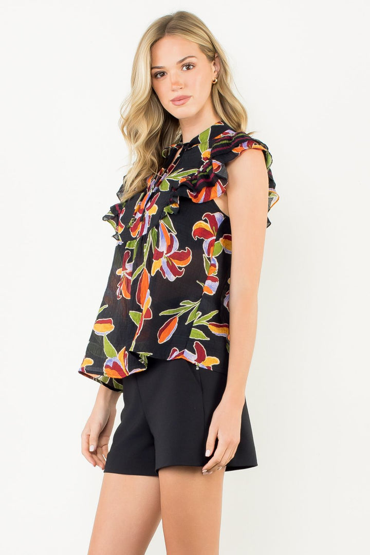 Woman wearing a colorful floral blouse and black shorts on a white background