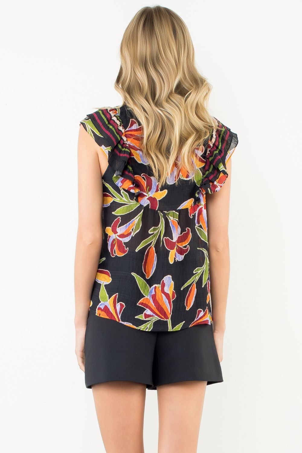 Woman wearing a sleeveless floral top and black shorts on a white background