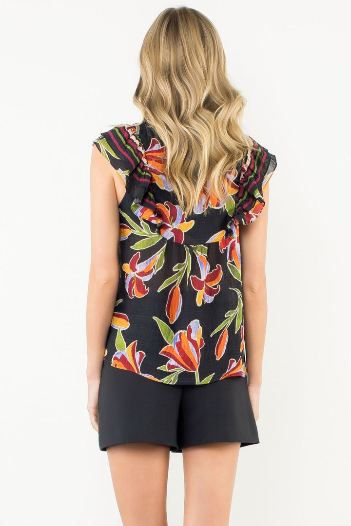 Woman wearing a sleeveless floral top and black shorts on a white background