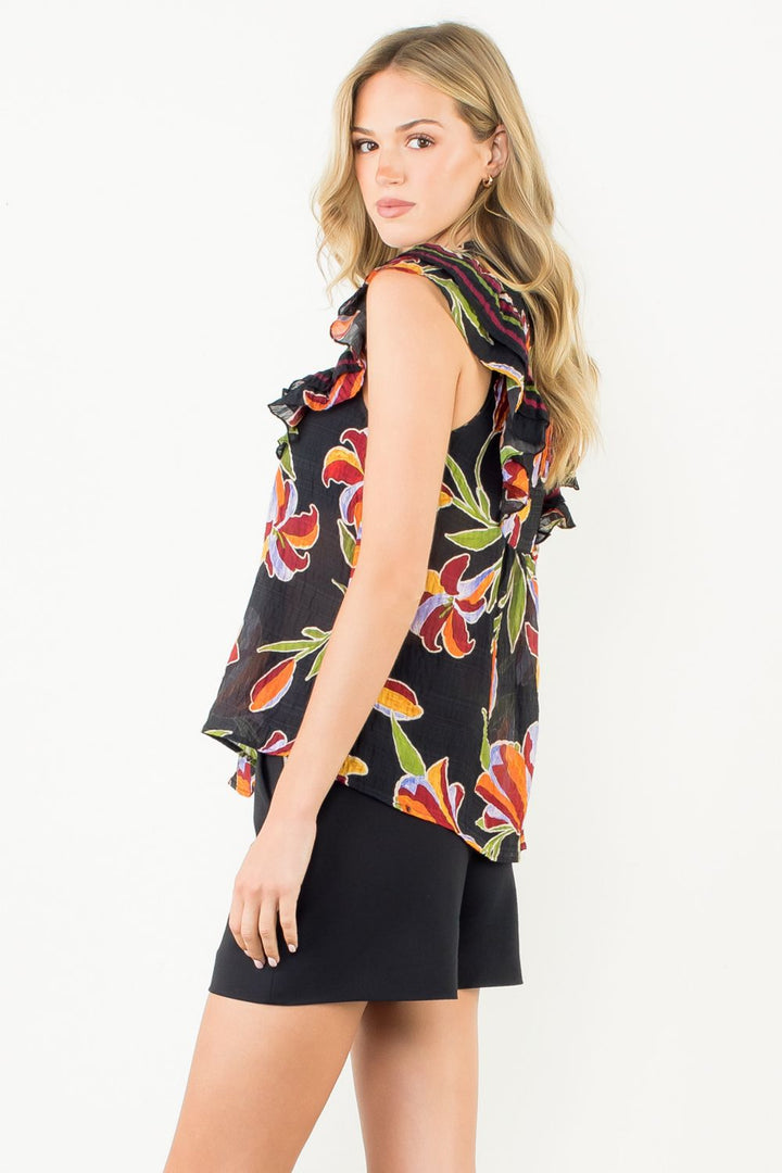 Woman wearing a sleeveless floral top and black shorts on a white background