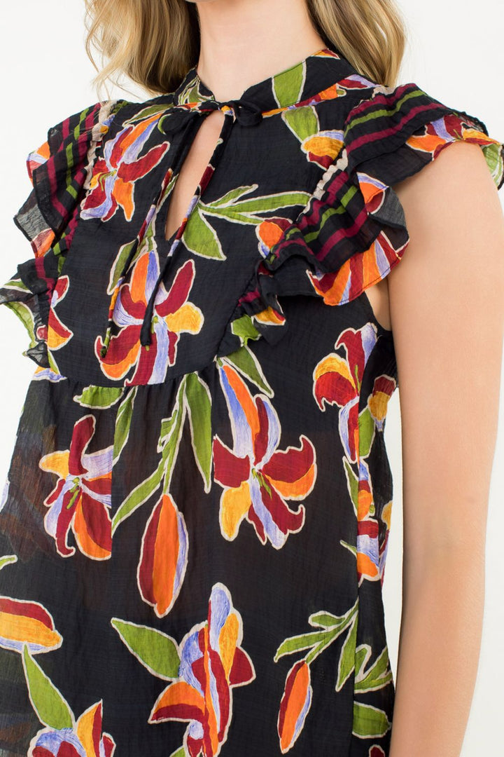 Woman wearing a black dress with colorful floral patterns on a white background