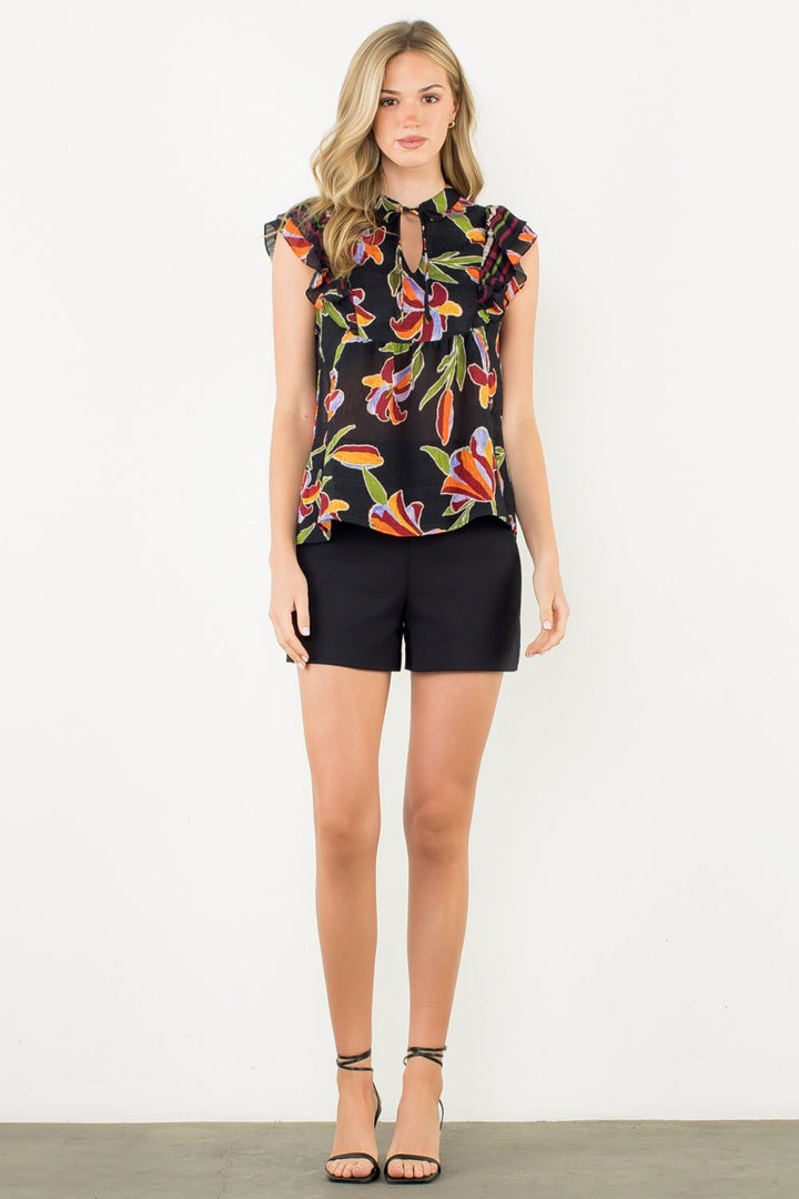 Woman wearing a black floral blouse and black shorts on a white background