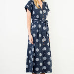 Woman wearing a navy dress with gray polka dots on a white background
