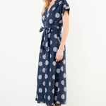 Woman wearing a navy dress with white polka dots against a white background