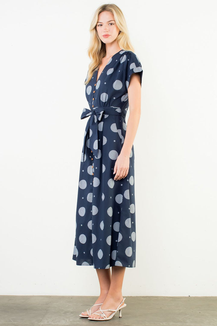 Woman wearing a navy dress with white polka dots against a white background