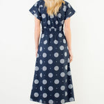 Woman wearing a navy dress with white polka dots against a white background