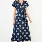 Woman wearing a navy dress with white polka dots against a white background